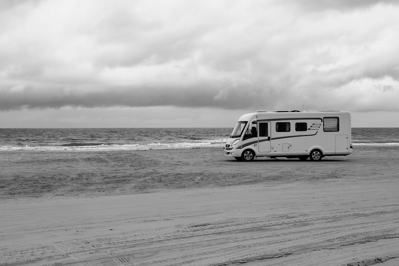 RV parked on a serene beach in Denmark with overcast skies.